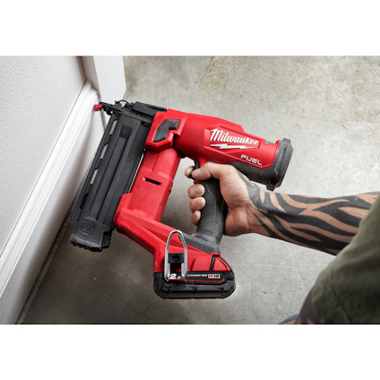 Bärbar röd och svart spikpistol med texten "Milwaukee Fuel" används för att fästa en list mot en vit vägg.