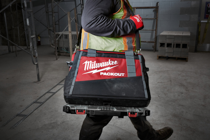 Person bär Milwaukee Packout-väska med rött och svart mönster.