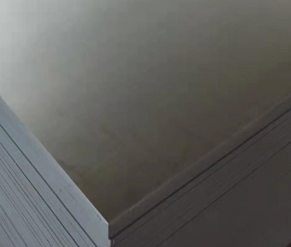 Högblank och slät yta av en mörk formplywoodskiva med skarpa, rena kanter.