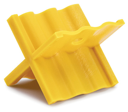 Gult plastföremål med vågformad design, format som ett kors, sannolikt en distanshållare.