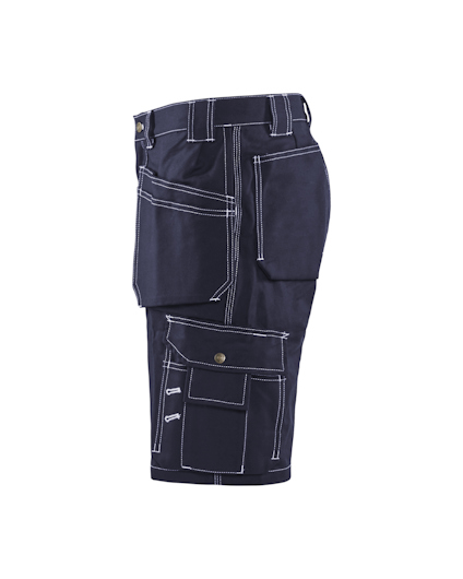Mörkblå arbetsbyxa med flera fickor och vita sömmar, sedd från sidan.