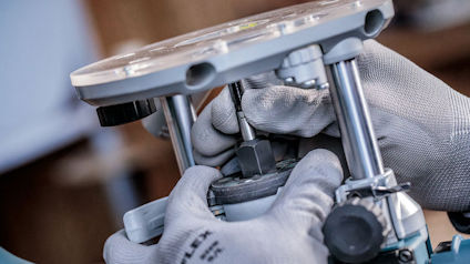 Händer i arbetshandskar hanterar metallverktyg och komponenter på nära håll.