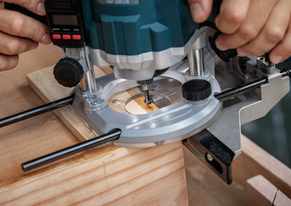 Person använder handöverfräs på träbit med styrskena för precision.