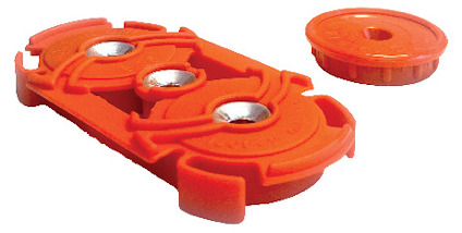 Orange plastkomponent med två metalldelar och en separat rund skiva.