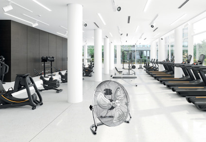 Ljust gym med träningscyklar, löpband och en stor fläkt i förgrunden.